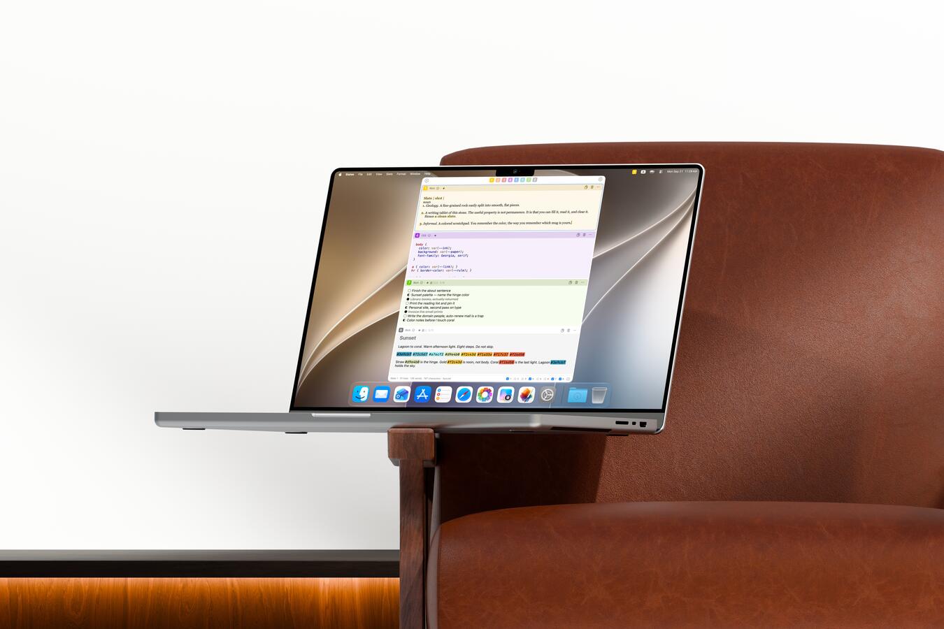 A MacBook Pro on the arm of a brown leather chair, Slates open to a column of pale slates in Light.